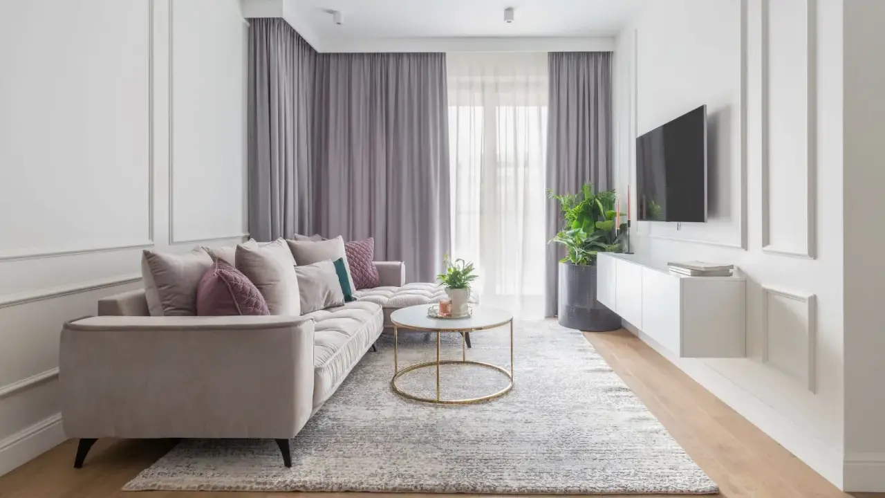 Eleganckie mieszkanie w stylu modern classic z jasną sofą, złotym stolikiem kawowym i dywanem.