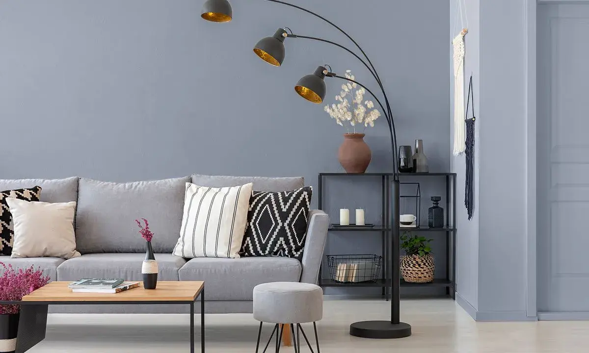 Nowoczesny salon z szarą kanapą i stolikiem kawowym. Bardzo jasny szary kolor ścian tworzy spokojną atmosferę.