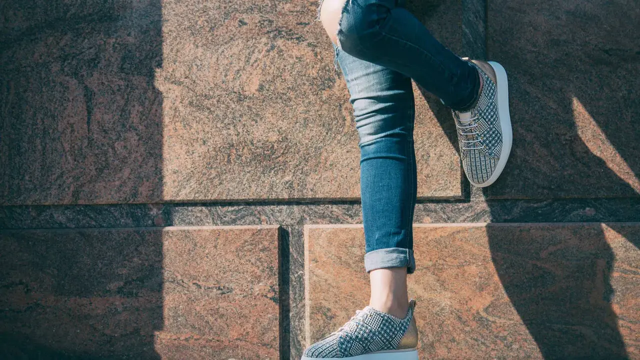 Nogawki jeansów podwinięte na kostkę, odsłaniające stylowe sneakersy. Idealny sposób, jak podwinąć spodnie jeansowe, by podkreślić obuwie.