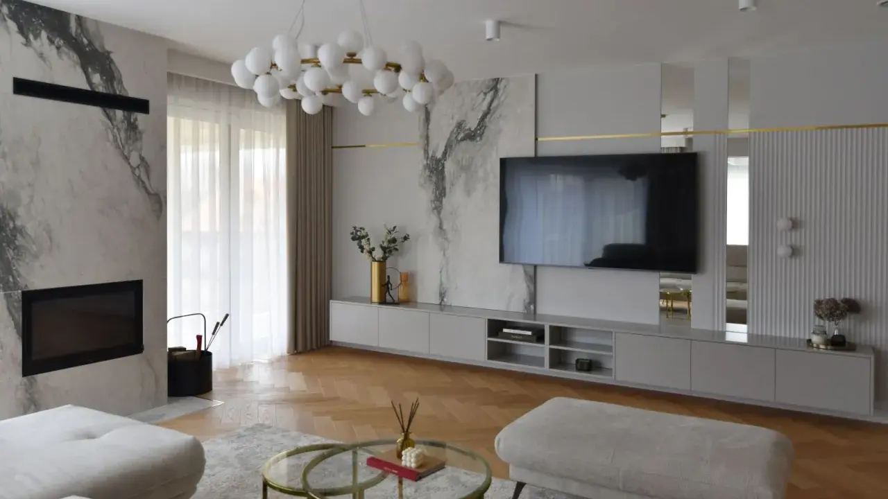 Elegancka ściana z TV glamour, z marmurowymi akcentami i złotymi detalami.