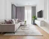 Eleganckie mieszkanie w stylu modern classic z jasną sofą, złotym stolikiem kawowym i dywanem.