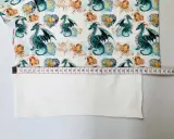 Miarka krawiecka pokazuje, jak poszerzyć bluzkę po bokach. Materiał z motywem smoków i serc.