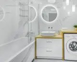 Nowoczesne, małe łazienki z wanną, umywalką nablatową i pralką. Marmurowe płytki i okrągłe lustro z podświetleniem tworzą elegancki styl.