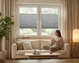 Kobieta pije kawę w salonie w stylu japandi. Jasna sofa, duża roślina i minimalistyczne dodatki tworzą przytulną atmosferę.