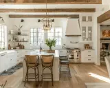 Jasna kuchnia w stylu farmhouse z drewnianymi belkami, wyspą i rattanowymi hokerami.