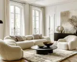 Przytulny salon w stylu modern classic z puszystymi meblami, czarnym stolikiem kawowym i abstrakcyjnym obrazem.