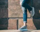 Nogawki jeansów podwinięte na kostkę, odsłaniające stylowe sneakersy. Idealny sposób, jak podwinąć spodnie jeansowe, by podkreślić obuwie.