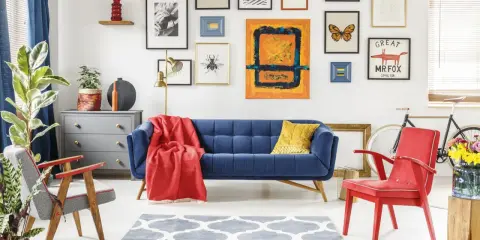 Salon w stylu eklektyzm: granatowa kanapa, czerwony fotel, dywan z geometrycznym wzorem, galeria obrazów na ścianie.