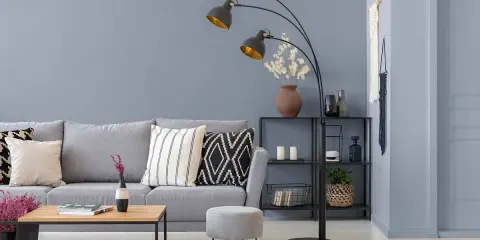 Nowoczesny salon z szarą kanapą i stolikiem kawowym. Bardzo jasny szary kolor ścian tworzy spokojną atmosferę.