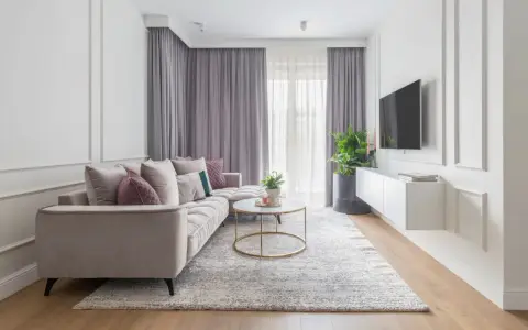 Eleganckie mieszkanie w stylu modern classic z jasną sofą, złotym stolikiem kawowym i dywanem.