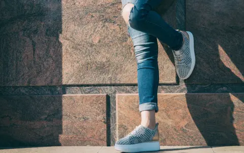 Nogawki jeansów podwinięte na kostkę, odsłaniające stylowe sneakersy. Idealny sposób, jak podwinąć spodnie jeansowe, by podkreślić obuwie.