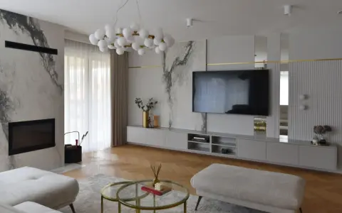 Elegancka ściana z TV glamour, z marmurowymi akcentami i złotymi detalami.