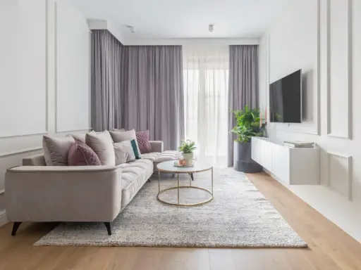 Eleganckie mieszkanie w stylu modern classic z jasną sofą, złotym stolikiem kawowym i dywanem.