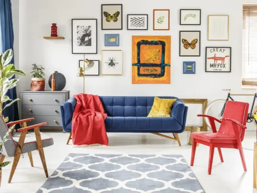 Salon w stylu eklektyzm: granatowa kanapa, czerwony fotel, dywan z geometrycznym wzorem, galeria obrazów na ścianie.