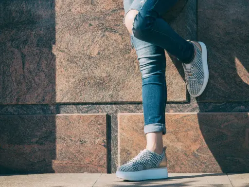 Nogawki jeansów podwinięte na kostkę, odsłaniające stylowe sneakersy. Idealny sposób, jak podwinąć spodnie jeansowe, by podkreślić obuwie.