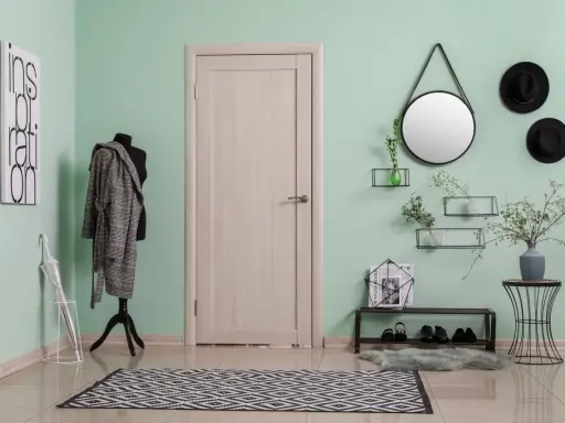 Przedpokój z miętowym kolorem ścian, manekin w płaszczu, lustro, półki z dekoracjami i drzwi.