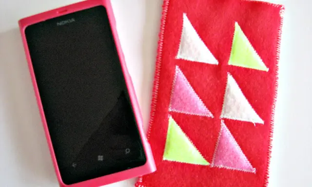 Różowe etui na telefon Nokia obok czerwonego pokrowca z kolorowymi trójkątami. Idealne, by pokazać, jak uszyć etui na telefon.