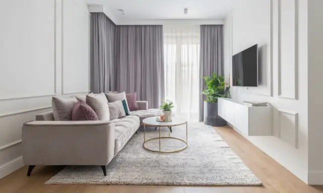 Eleganckie mieszkanie w stylu modern classic z jasną sofą, złotym stolikiem kawowym i dywanem.