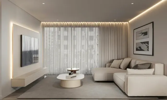 Nowoczesny salon w stylu minimalizm we wnętrzach. Jasna kanapa, telewizor na ścianie, owalny stolik kawowy i subtelne oświetlenie tworzą spokojną atmosferę.