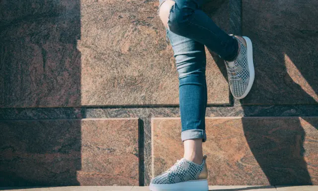 Nogawki jeansów podwinięte na kostkę, odsłaniające stylowe sneakersy. Idealny sposób, jak podwinąć spodnie jeansowe, by podkreślić obuwie.