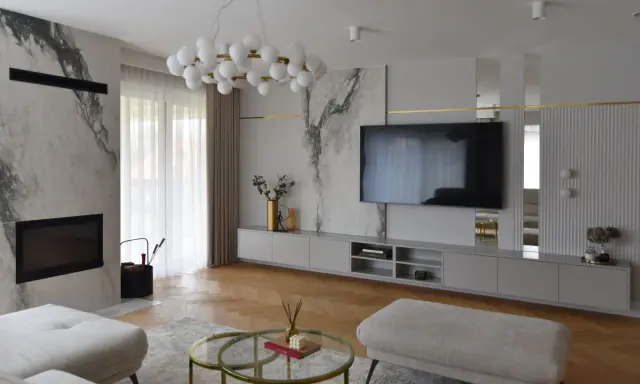 Elegancka ściana z TV glamour, z marmurowymi akcentami i złotymi detalami.