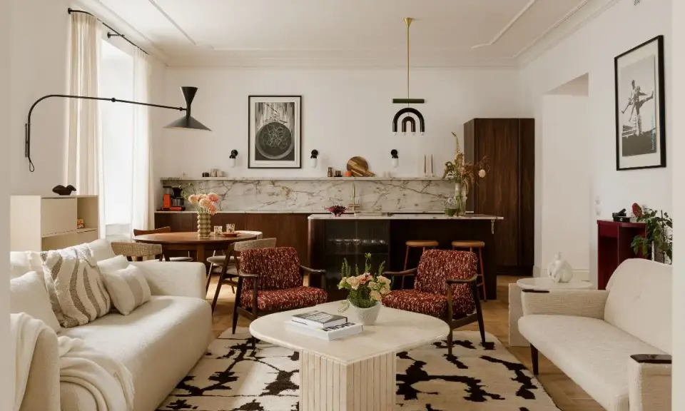 Przytulny salon z elementami styl vintage wnętrza: kremowa sofa, fotele w rudy wzór, okrągły stolik i dywan z geometrycznym motywem.