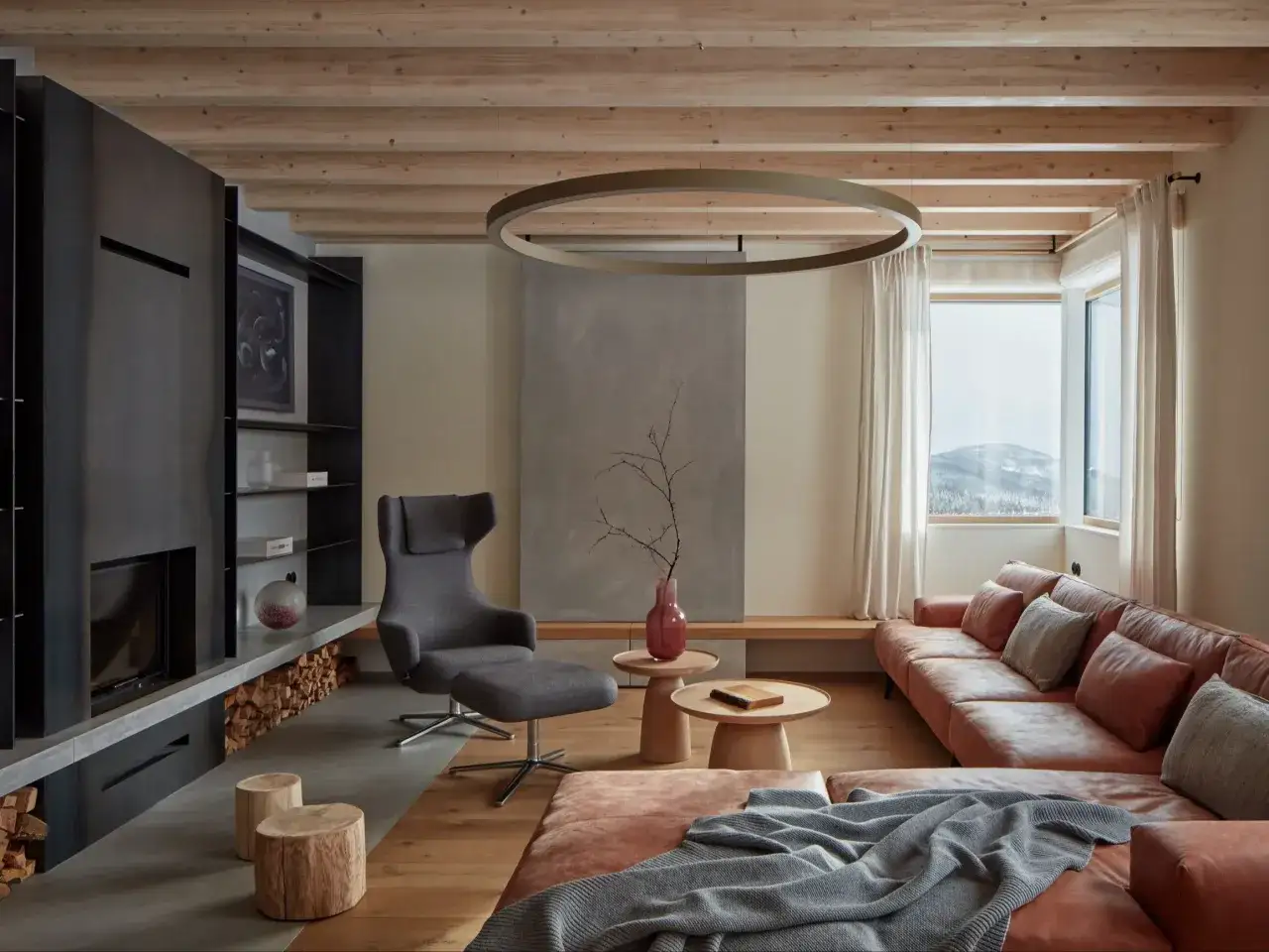 Nowoczesny salon w stylu modern farmhouse z kamiennym kominkiem, drewnianymi belkami na suficie i skórzaną kanapą.