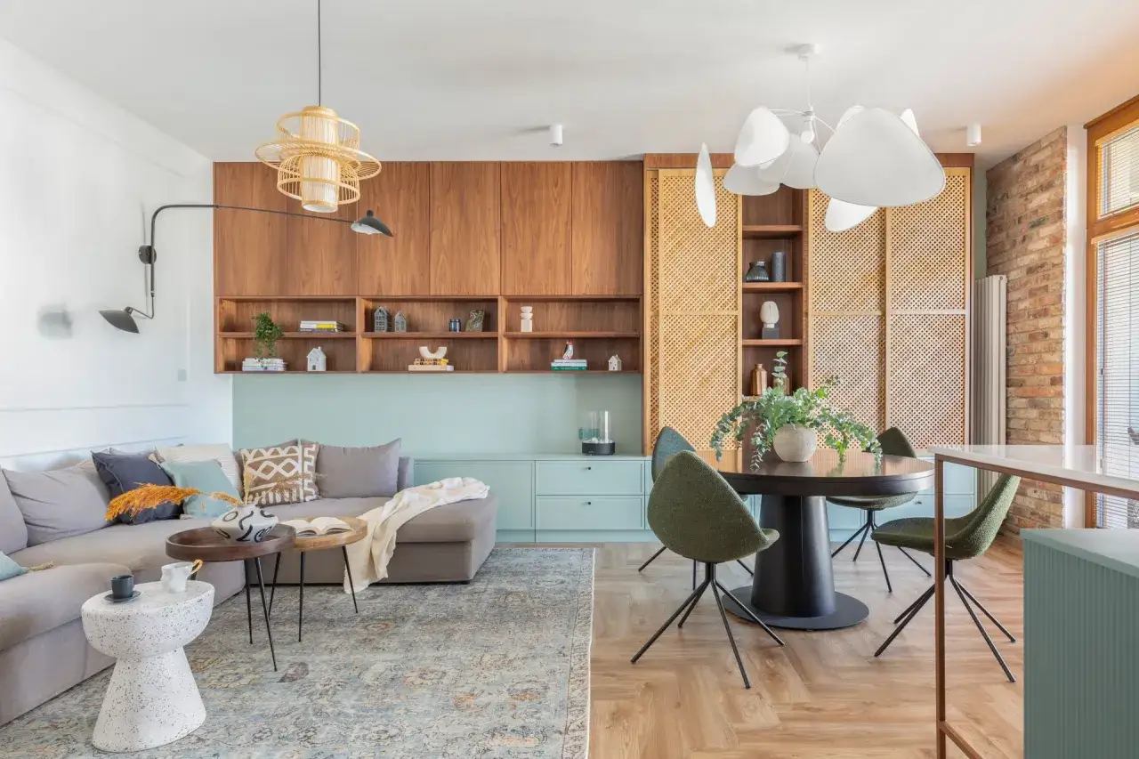 Przytulny salon z sofą, stolikami kawowymi i dywanem. Miętowy kolor ścian tworzy spokojną atmosferę, a drewniane meble dodają ciepła.
